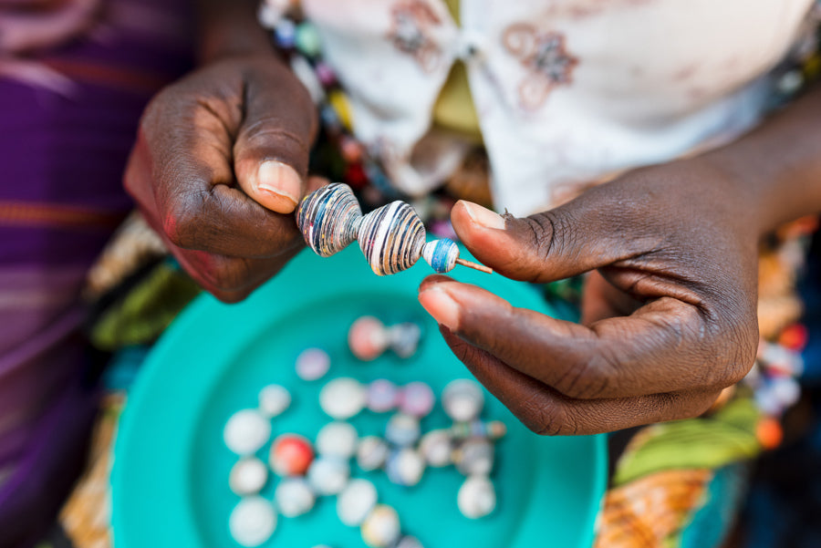 Afrikanische Frau rollt mit Fingern Papierperlen
